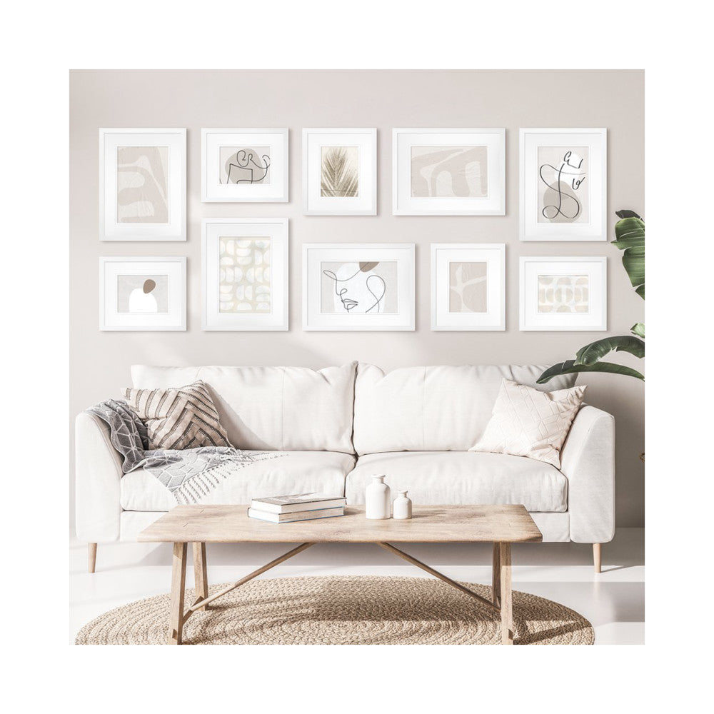 White framed gallery wall art collection displayed above a cream sofa with wooden coffee table and neutral decor.