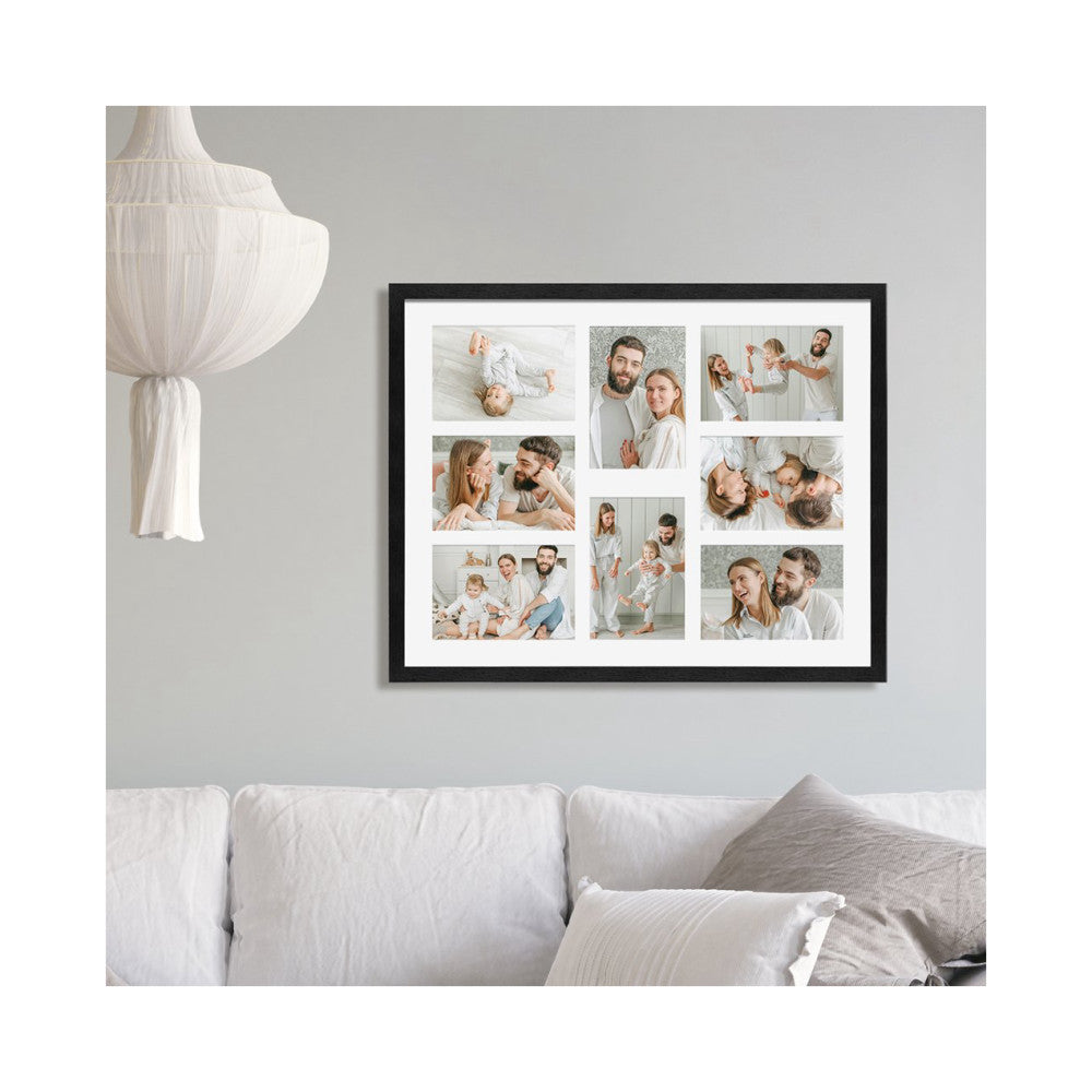 Black framed photo collage displaying eight 4x6 family photos mounted on a gray wall above a white sofa.