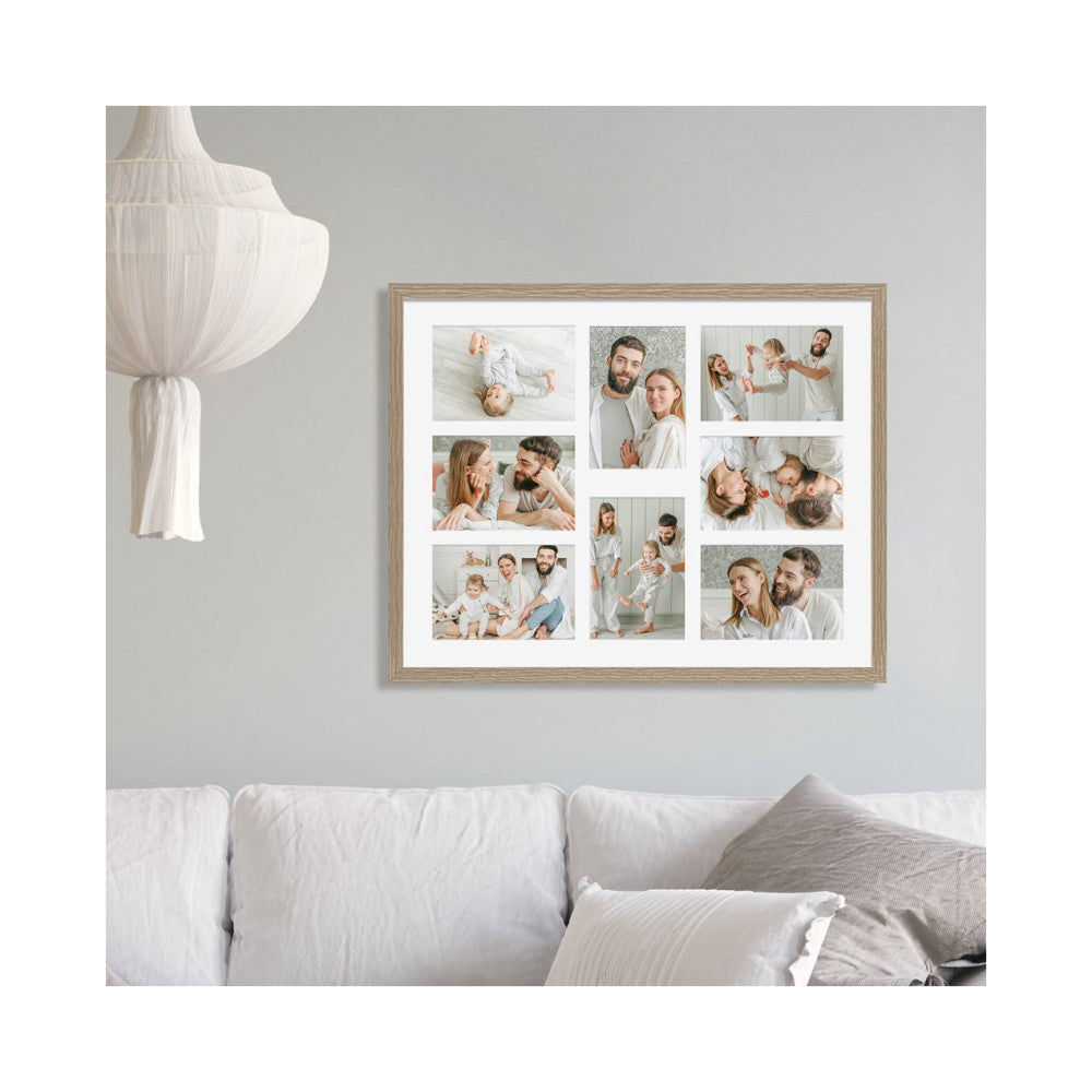 Framed multi-photo collage displaying eight 4x6 family photos in natural wood frame, mounted on gray wall above white sofa with decorative pendant light visible.