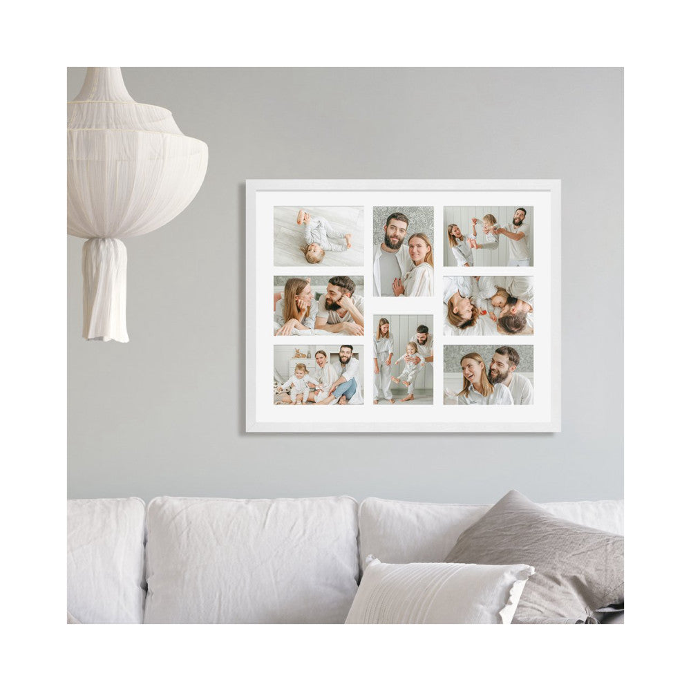 White framed photo collage displaying eight 4x6 family photos mounted on a gray wall above a white sofa.