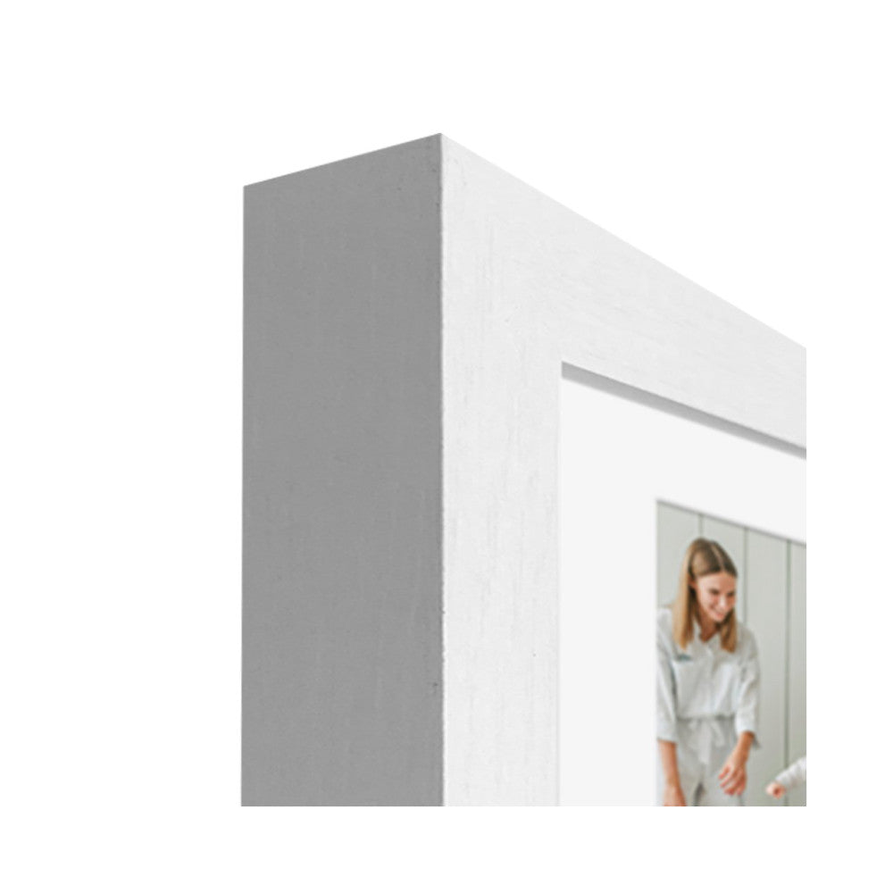 Close-up detail of white frame corner showing beveled edge and mat opening with reflected image of woman in white shirt