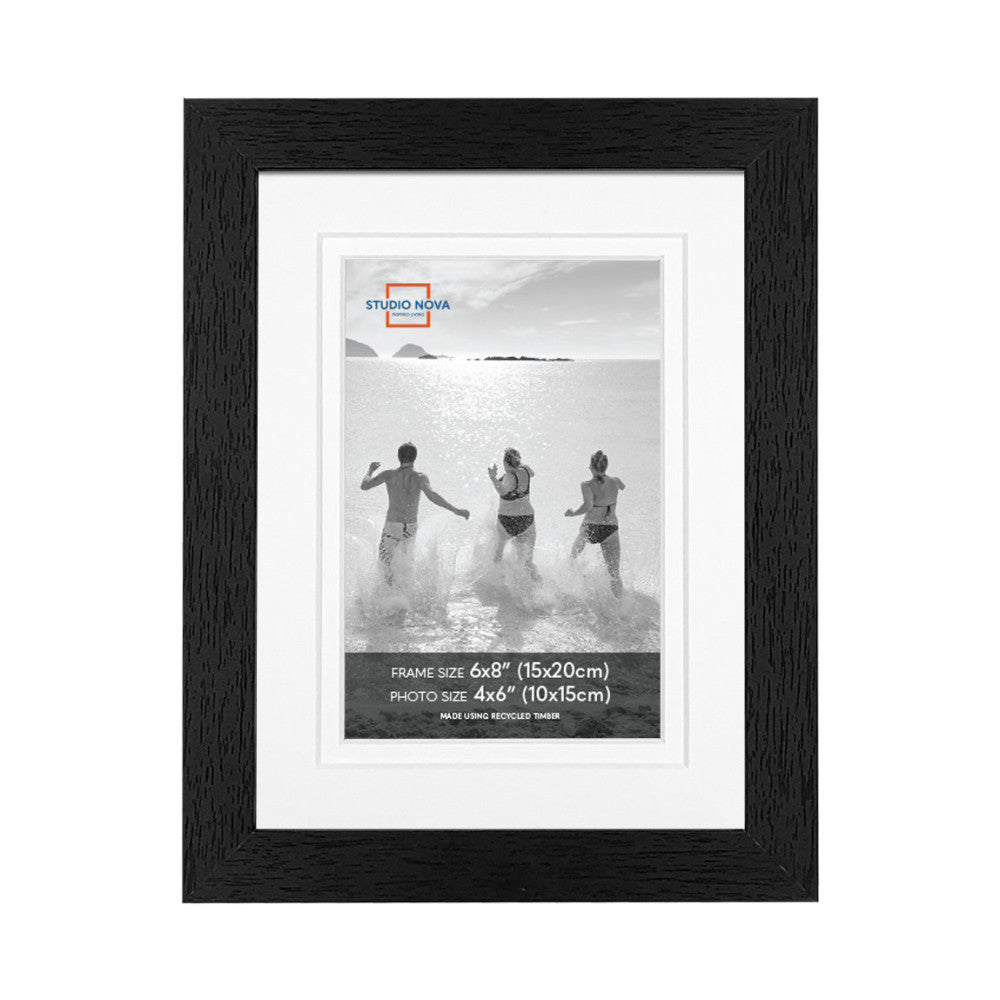 Black wooden picture frame with white matting displaying a black and white beach photo of people running into the ocean.