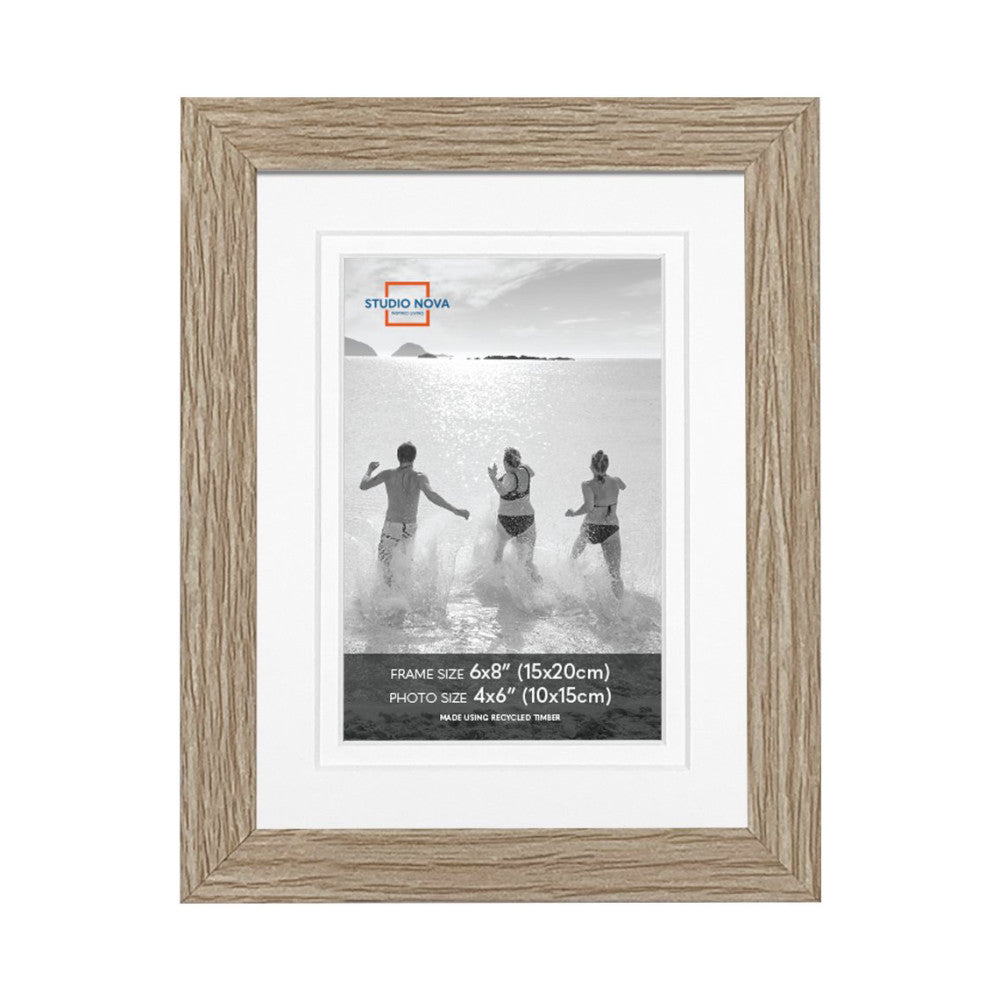 Front view of a wooden picture frame with white mat displaying a black and white beach photograph of three people running into the ocean.