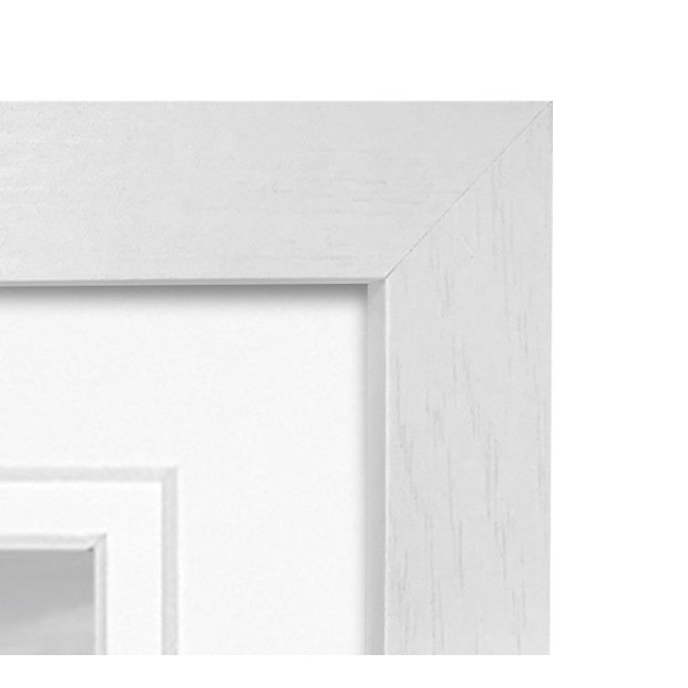Close-up detail of white wooden picture frames stacked at an angle, showing the corner and edge of the frame molding.