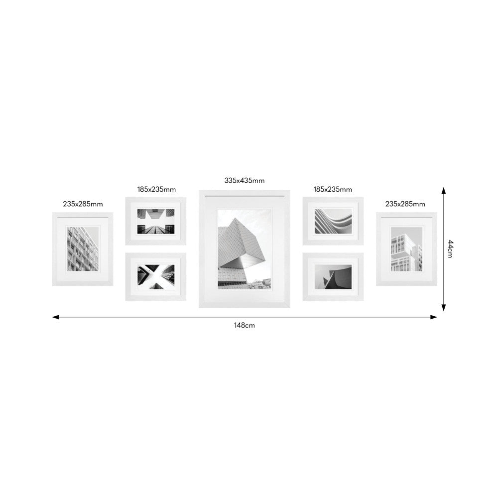 Top-down view of seven white frames arranged in a gallery wall layout with dimensions labeled, displaying black and white architectural photographs.