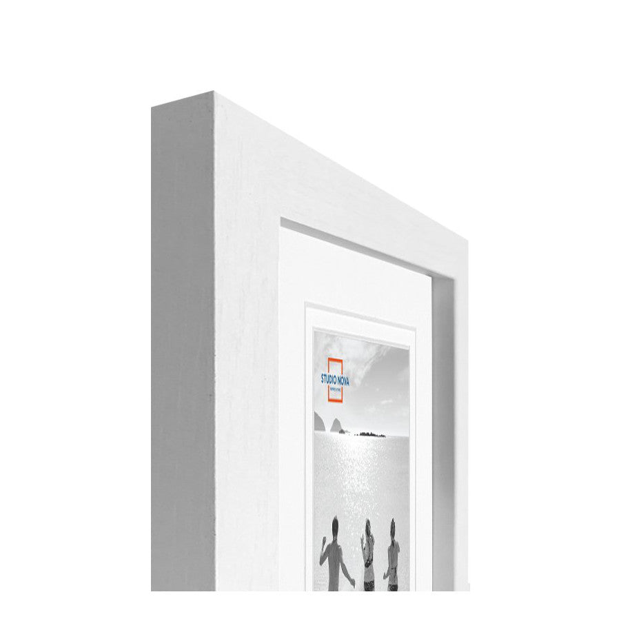 Angled side view of a white gallery wall frame displaying a black and white landscape photograph with people silhouettes.