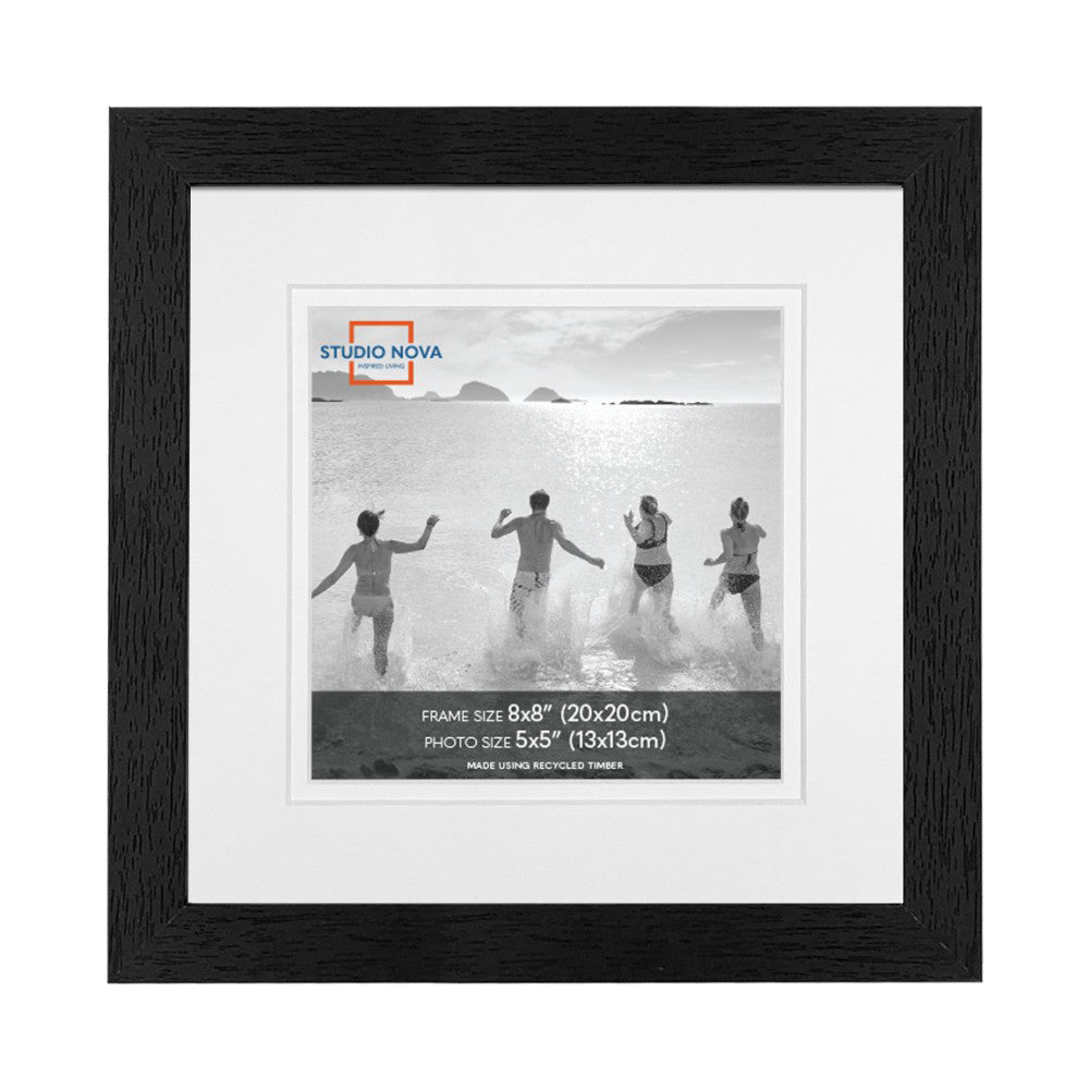 Black wooden frame displaying a matted black and white photo of five people running into the ocean, with Studio Nova branding visible.