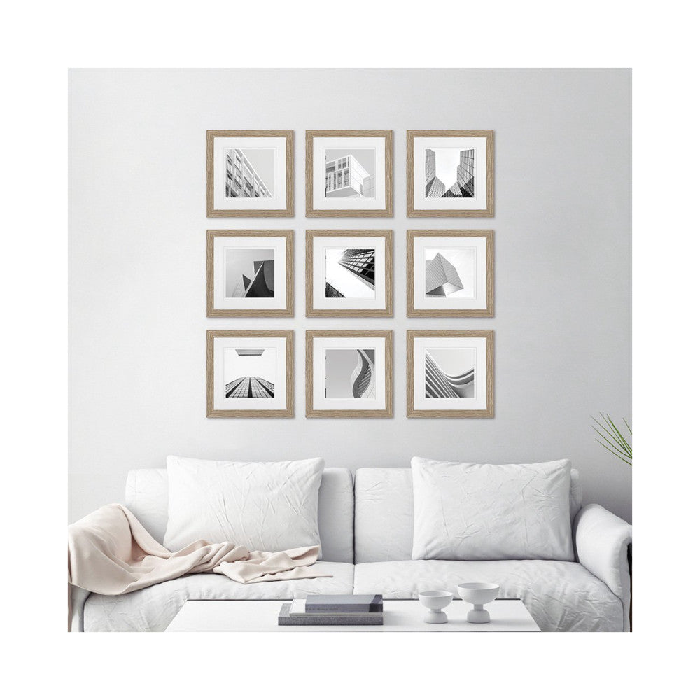 Nine wooden framed black and white architectural photographs arranged in a 3x3 grid on a light gray wall above a white sofa.