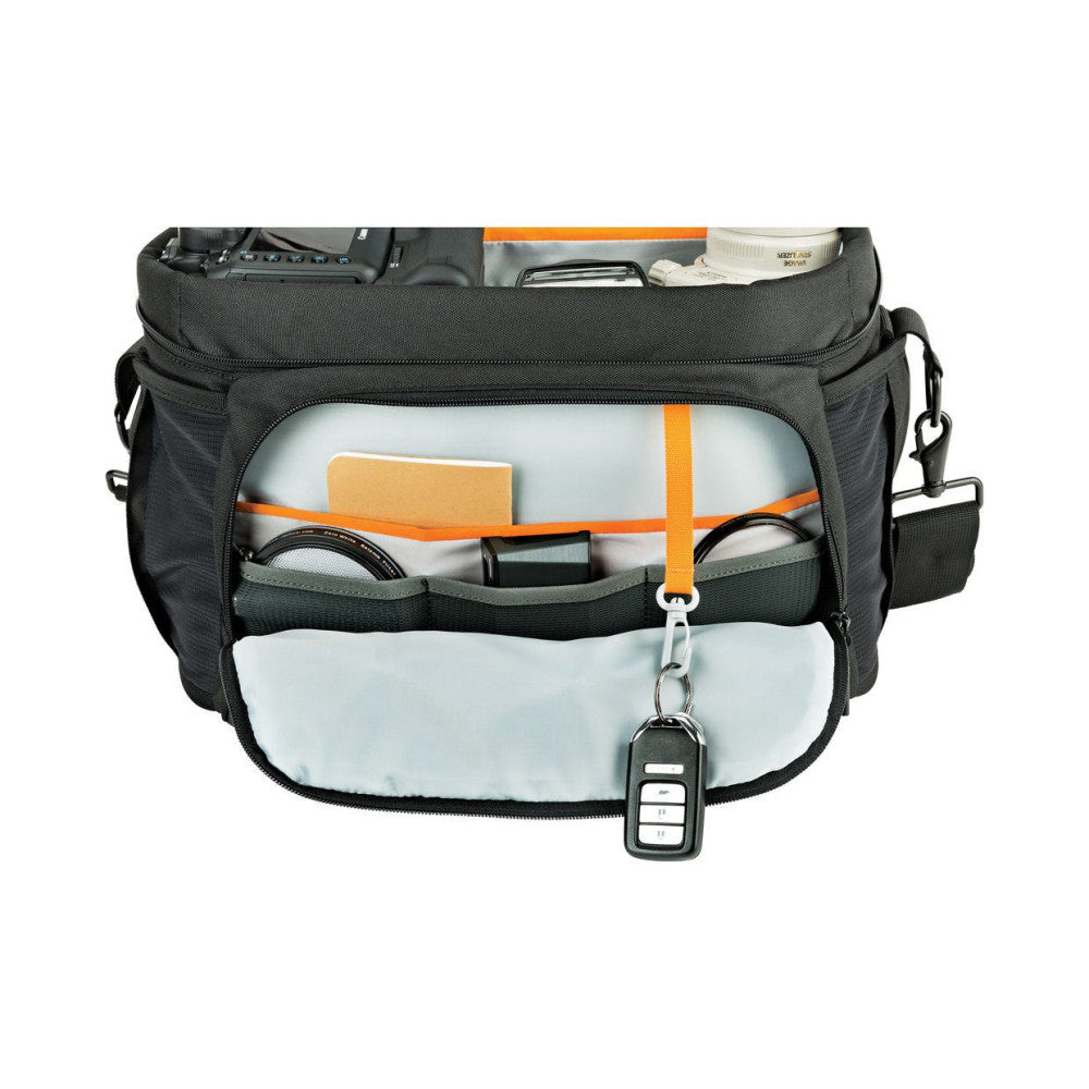 Open front view of black camera bag displaying organized compartments with orange accents, cables, and accessories inside, with key fob attached.